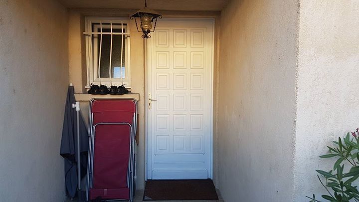 Avant les travaux : ancienne porte d'entrée blanche à petits panneaux sous un porche crépi