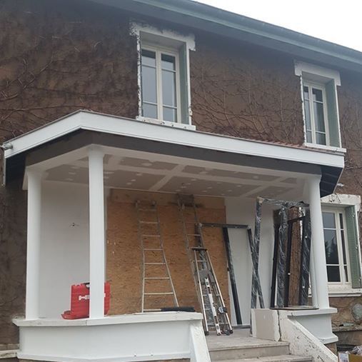 Avant les travaux : porche à colonnes blanches encore ouvert, devant une façade couverte de vigne vierge