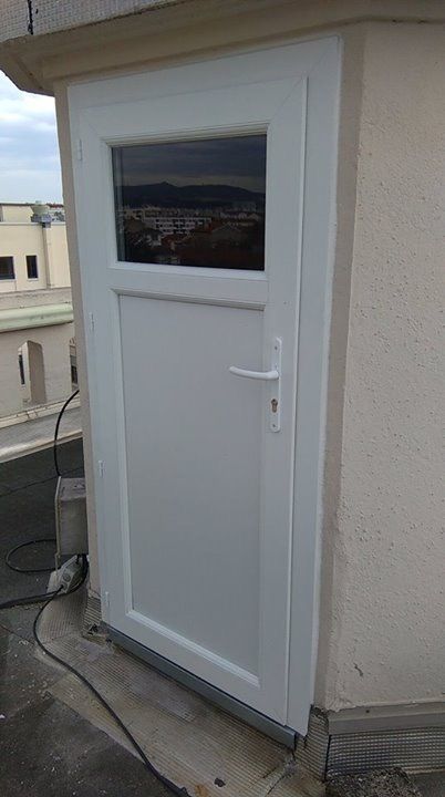 Après les travaux : porte blanche vitrée en partie haute, posée sur le même accès en toit-terrasse