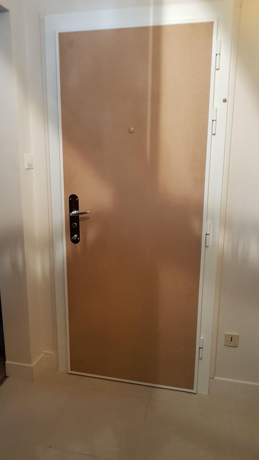 Porte d'appartement pleine finition beige avec serrure de sécurité, vue depuis l'intérieur