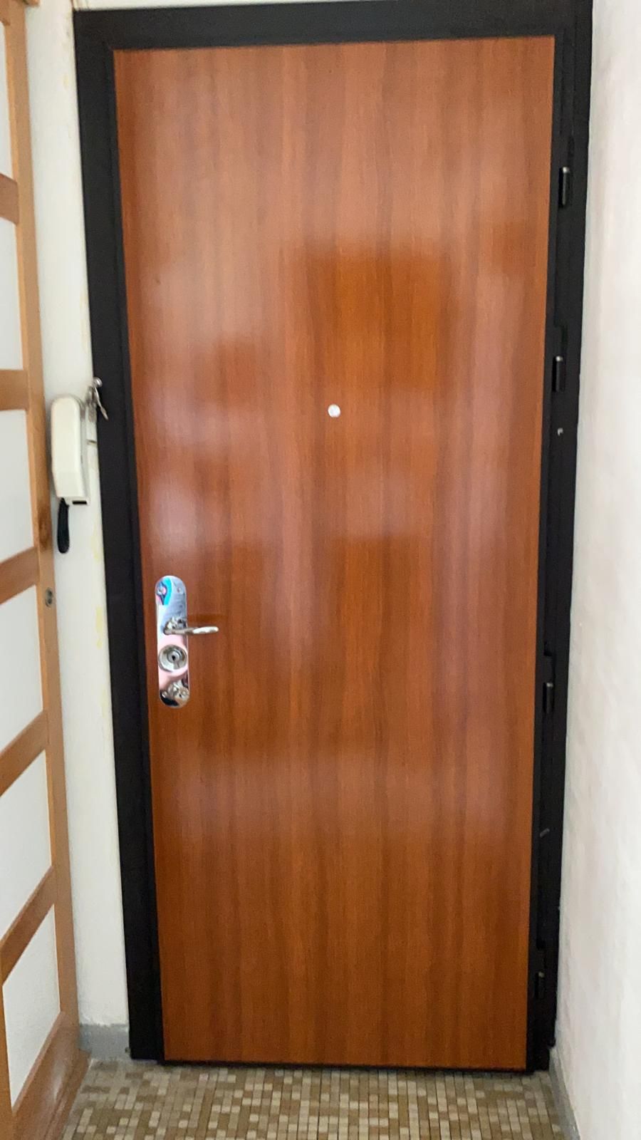 Porte blindée finition bois avec huisserie noire, dans une entrée d'appartement
