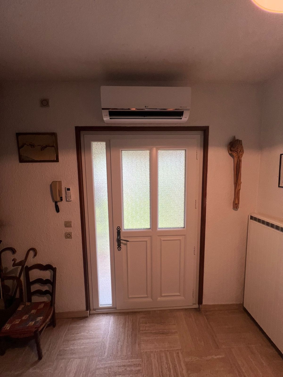 Climatisation murale installée au-dessus de la porte d'entrée d'un hall de maison