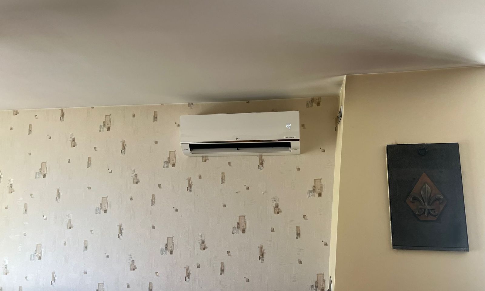 Unité intérieure de climatisation murale installée au-dessus d'un mur tapissé dans un séjour