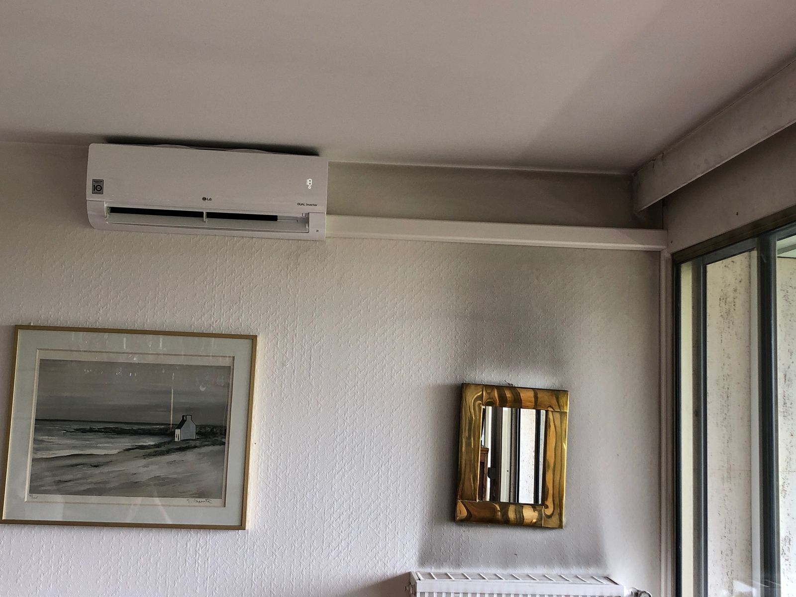 Unité intérieure de climatisation murale installée en haut d'un mur de séjour