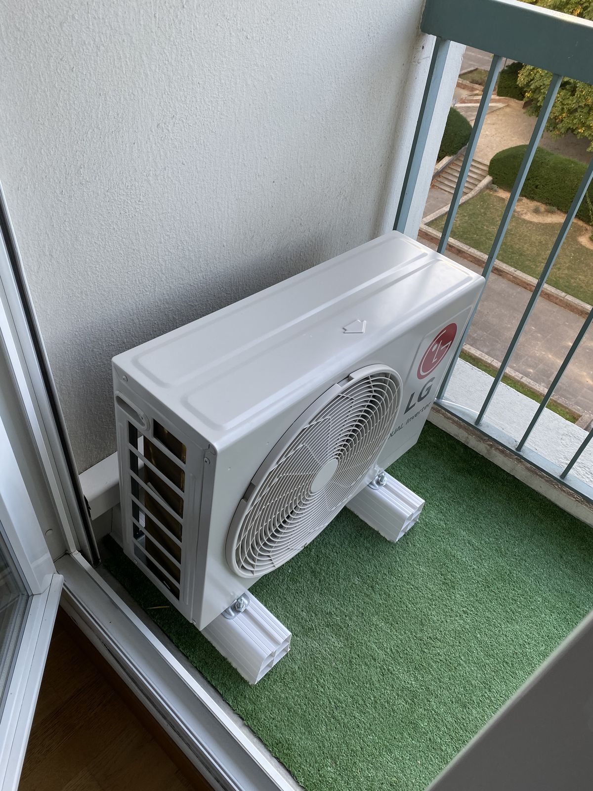 Unité extérieure de climatisation posée sur supports au sol d'un balcon
