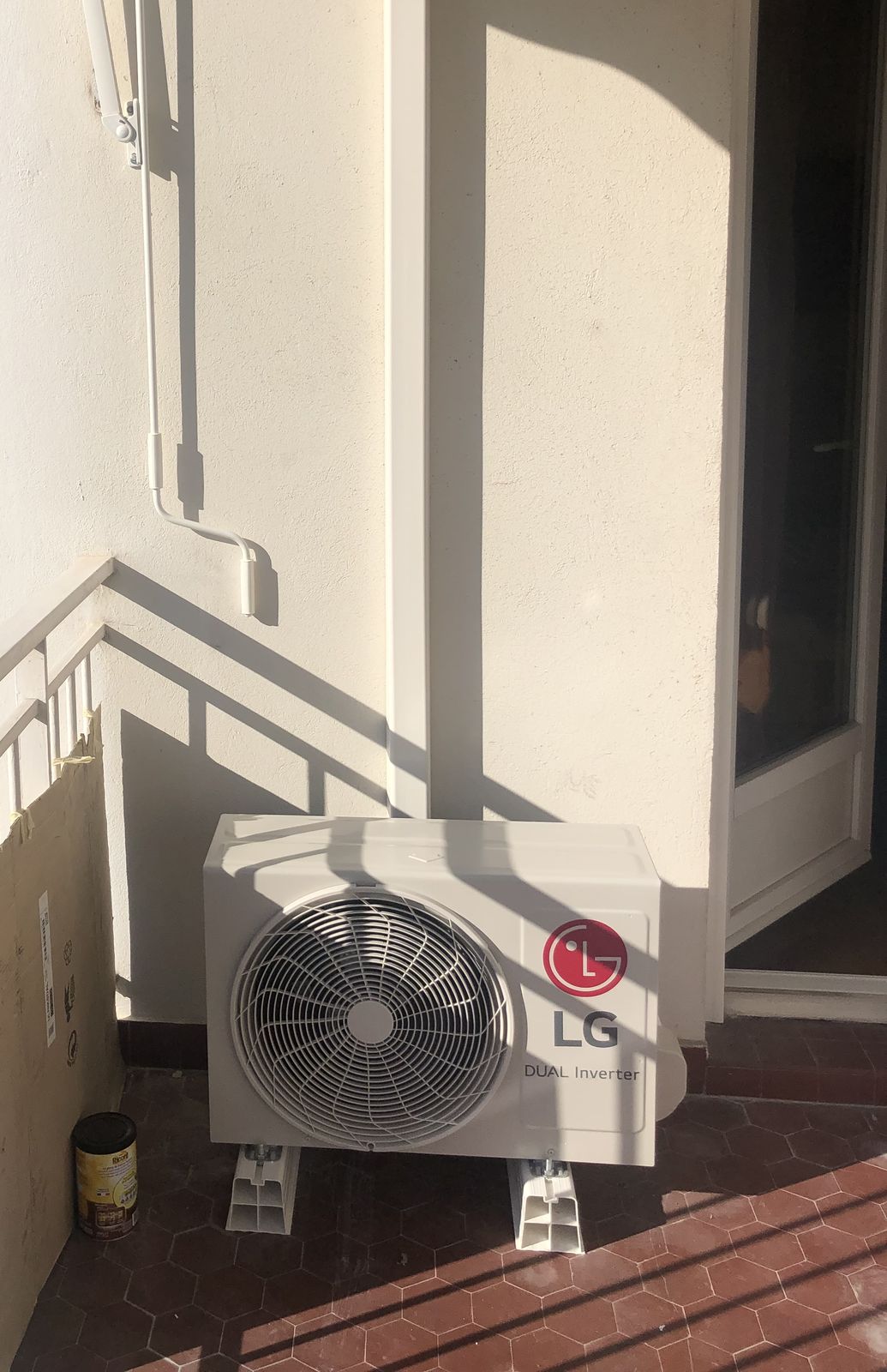 Unité extérieure de climatisation sur un balcon, liaisons protégées par une goulotte murale