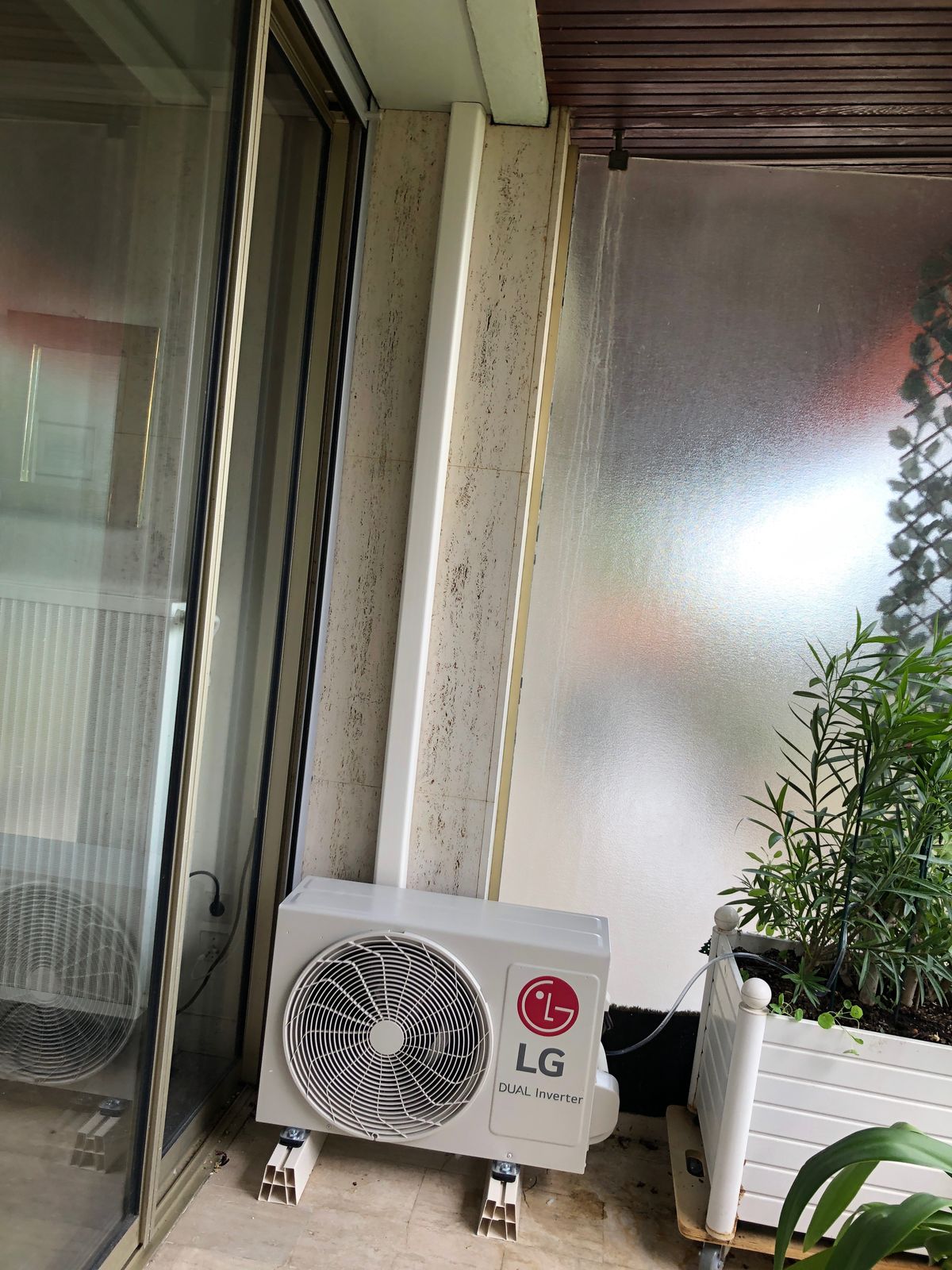 Unité extérieure de climatisation posée sur une loggia à côté de plantes