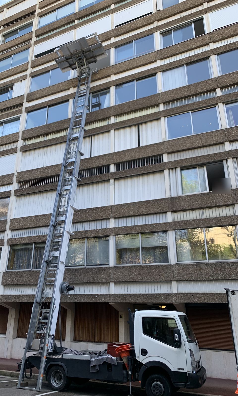 Camion équipé d'un monte-matériaux dont l'échelle monte le long de la façade d'un immeuble