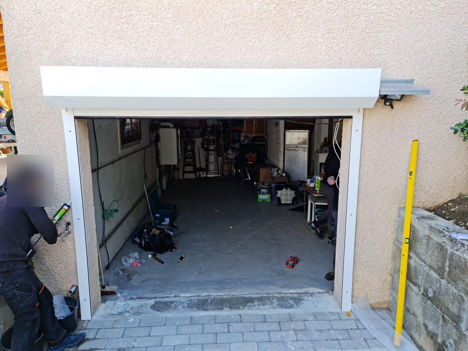 Poseur réalisant les joints de finition autour d'une porte de garage enroulable