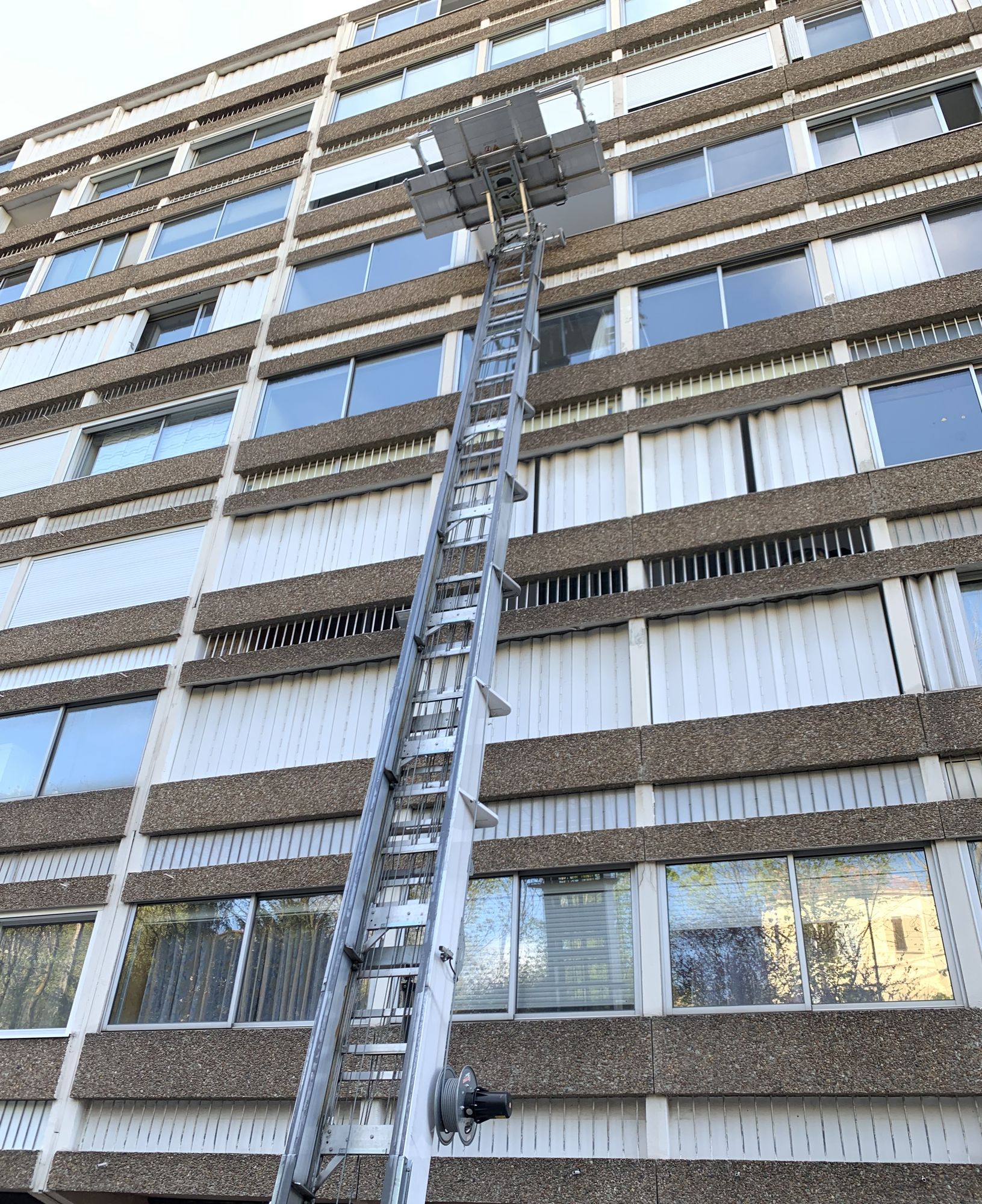 Monte-matériaux dressé contre la façade d'un immeuble pour livrer des menuiseries en étage