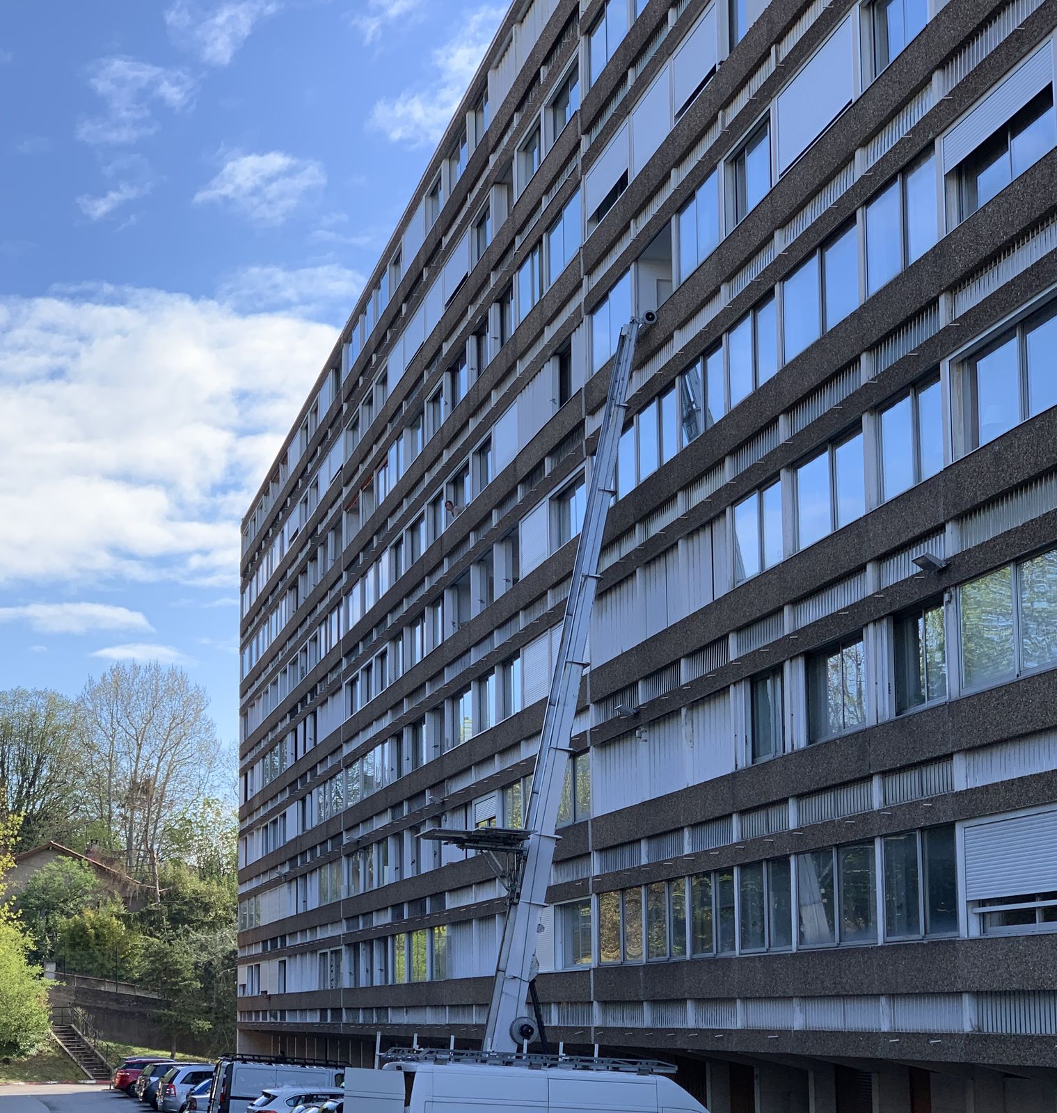 Monte-matériaux déployé contre un grand immeuble, utilitaire stationné au pied de la façade