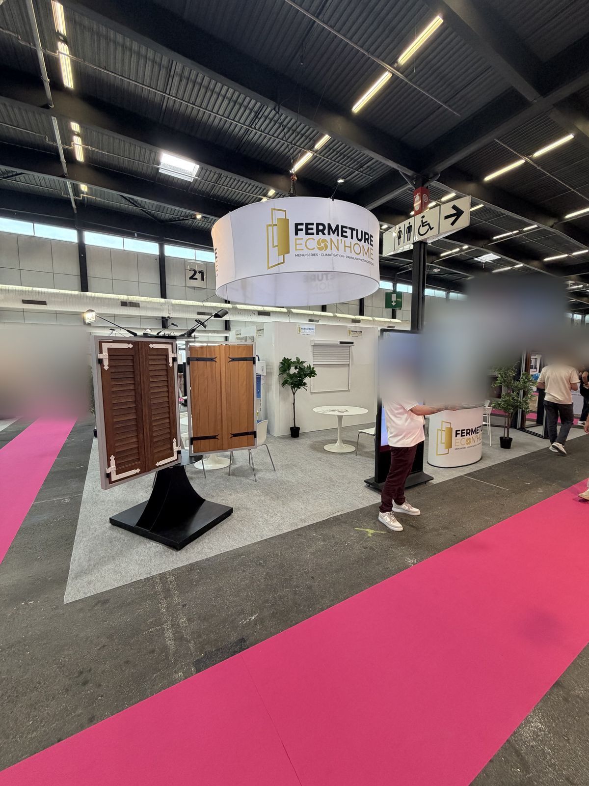 Stand au parc des expositions de Bordeaux-Lac : présentoir de volets battants ton bois, borne d'accueil et enseigne ronde Fermeture Econ'Home