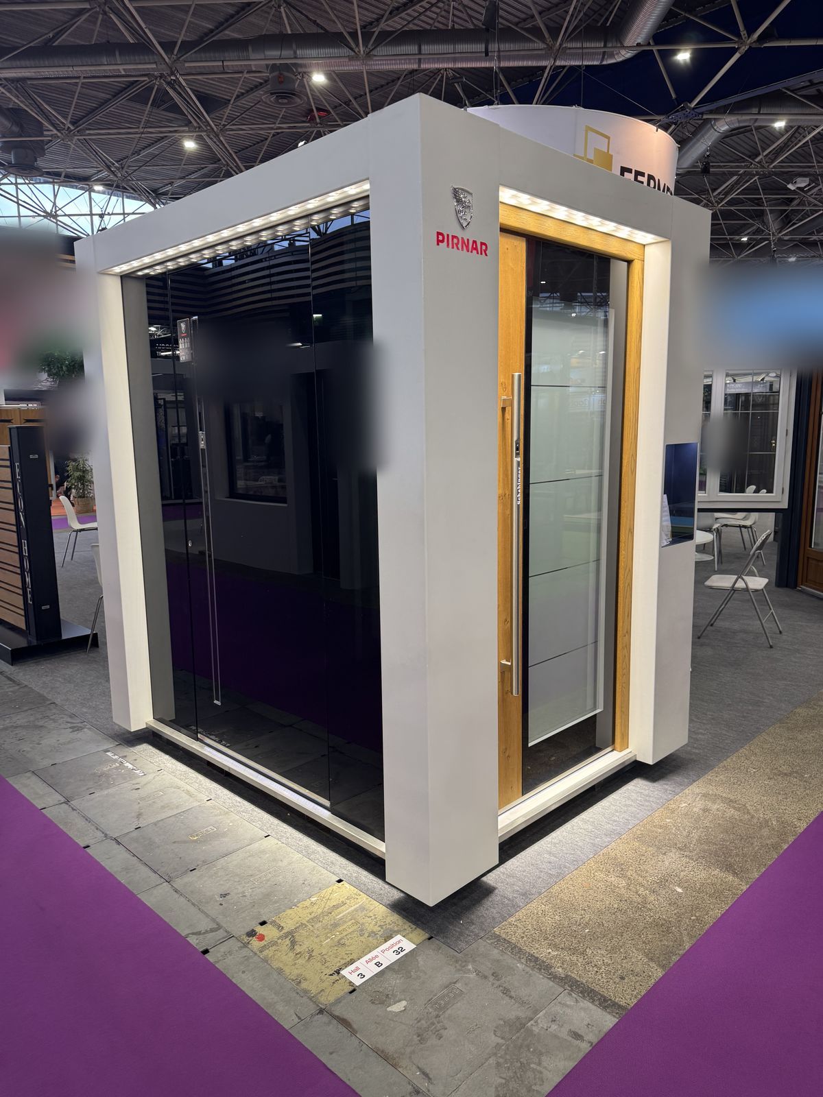 Cabine d'exposition Pirnar présentant une porte d'entrée vitrée noire et une porte ton bois