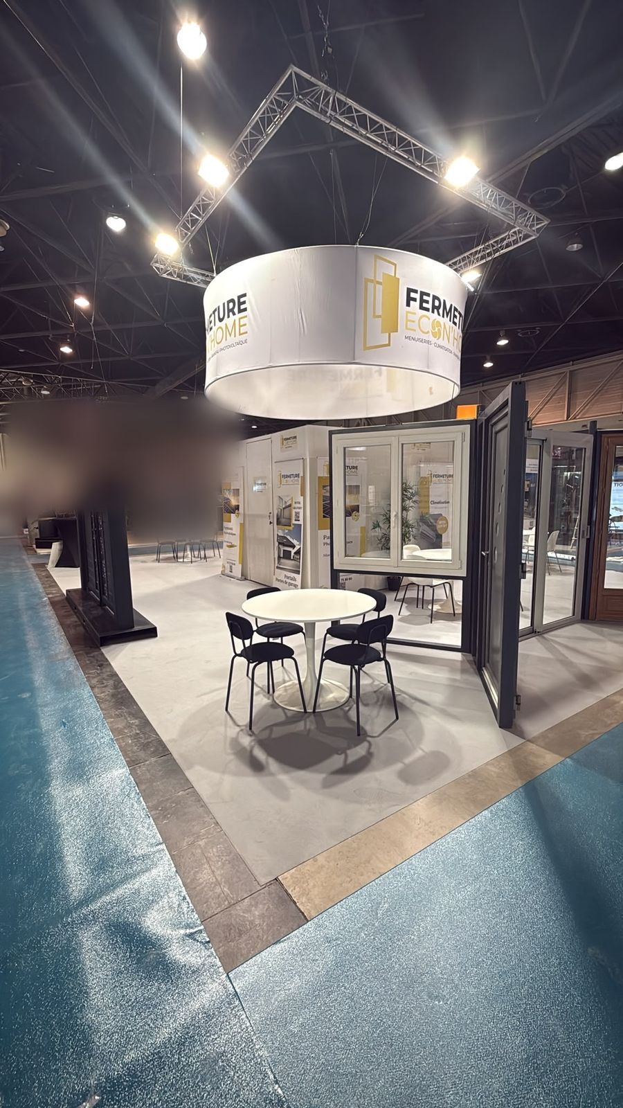 Fenêtres, porte-fenêtre et porte d'entrée noire exposées autour des tables du stand
