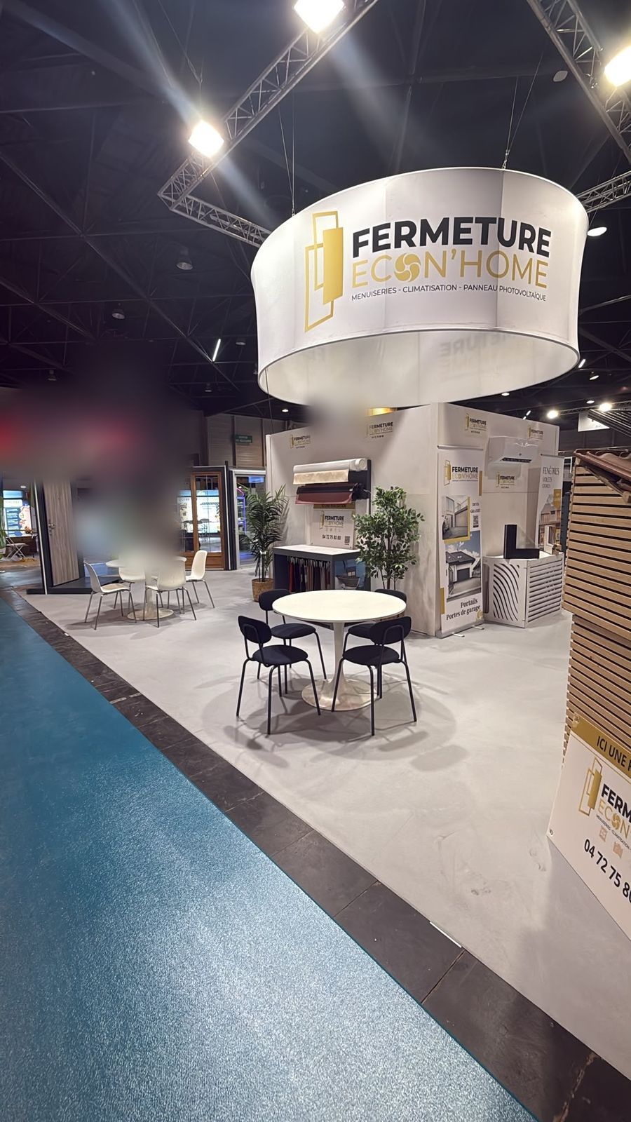 Le stand vu de côté : tables, fenêtres et présentoirs sous l'enseigne ronde