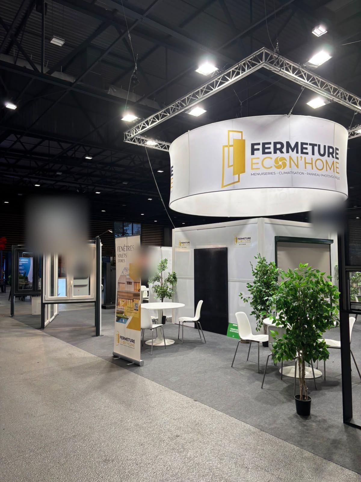 Stand Fermeture Econ'Home avec portes d'entrée et fenêtres exposées autour des tables d'accueil