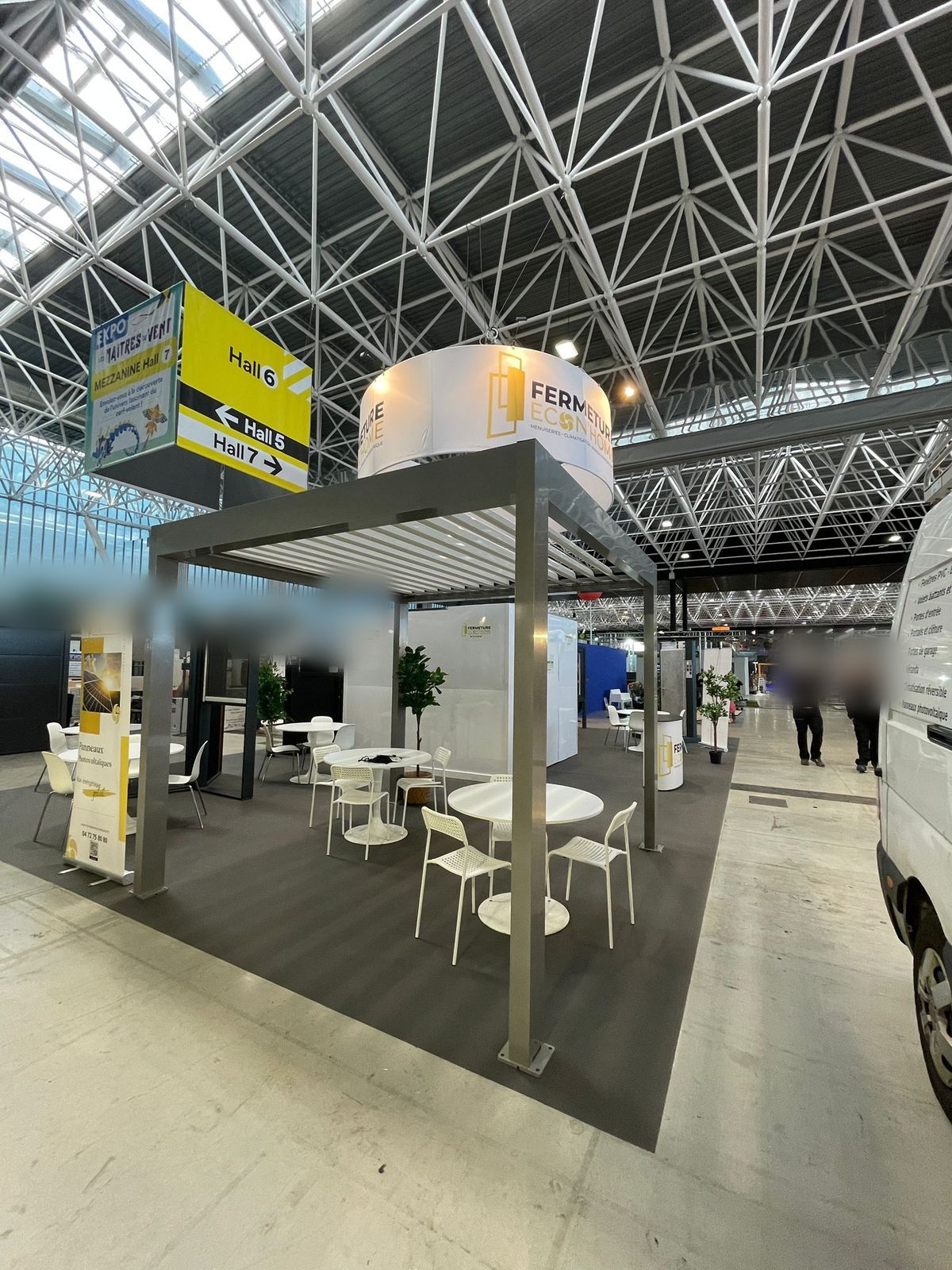 Pergola en aluminium avec tables et chaises blanches à l'angle du stand