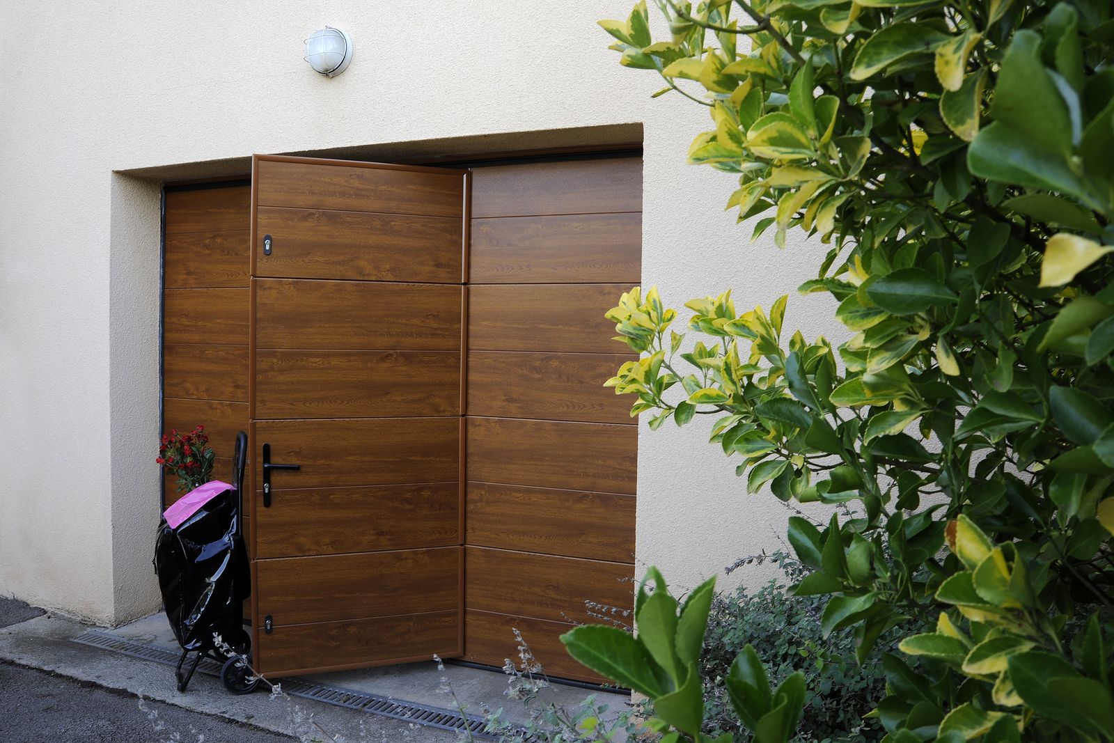 Porte de garage sectionnelle décor chêne doré à panneaux horizontaux, portillon intégré entrouvert