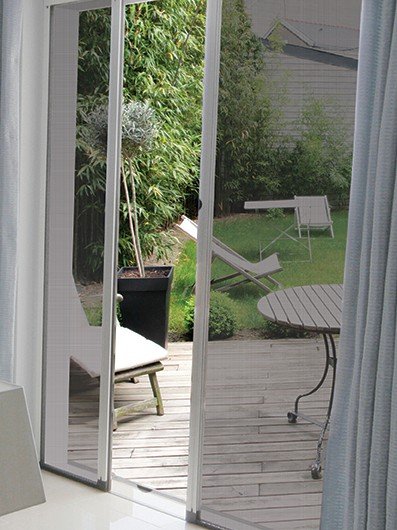 Moustiquaire à toile tendue coulissant devant une porte-fenêtre, avec vue sur une terrasse en bois