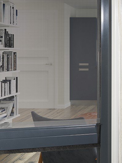 Moustiquaire enroulable VERTIGO baissée devant une fenêtre, profils gris anthracite et barre de charge en bas, pièce visible à travers la toile