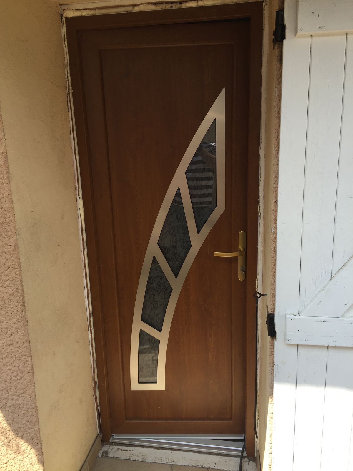Porte d'entrée ton bois avec un vitrage en arc cerclé d'inox et poignée dorée