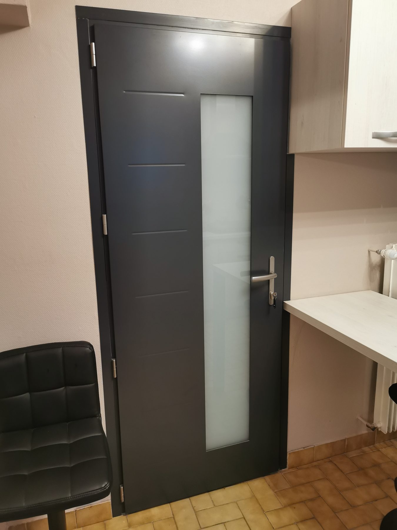 Porte gris anthracite à vitrage dépoli vertical, vue depuis l'intérieur d'un logement