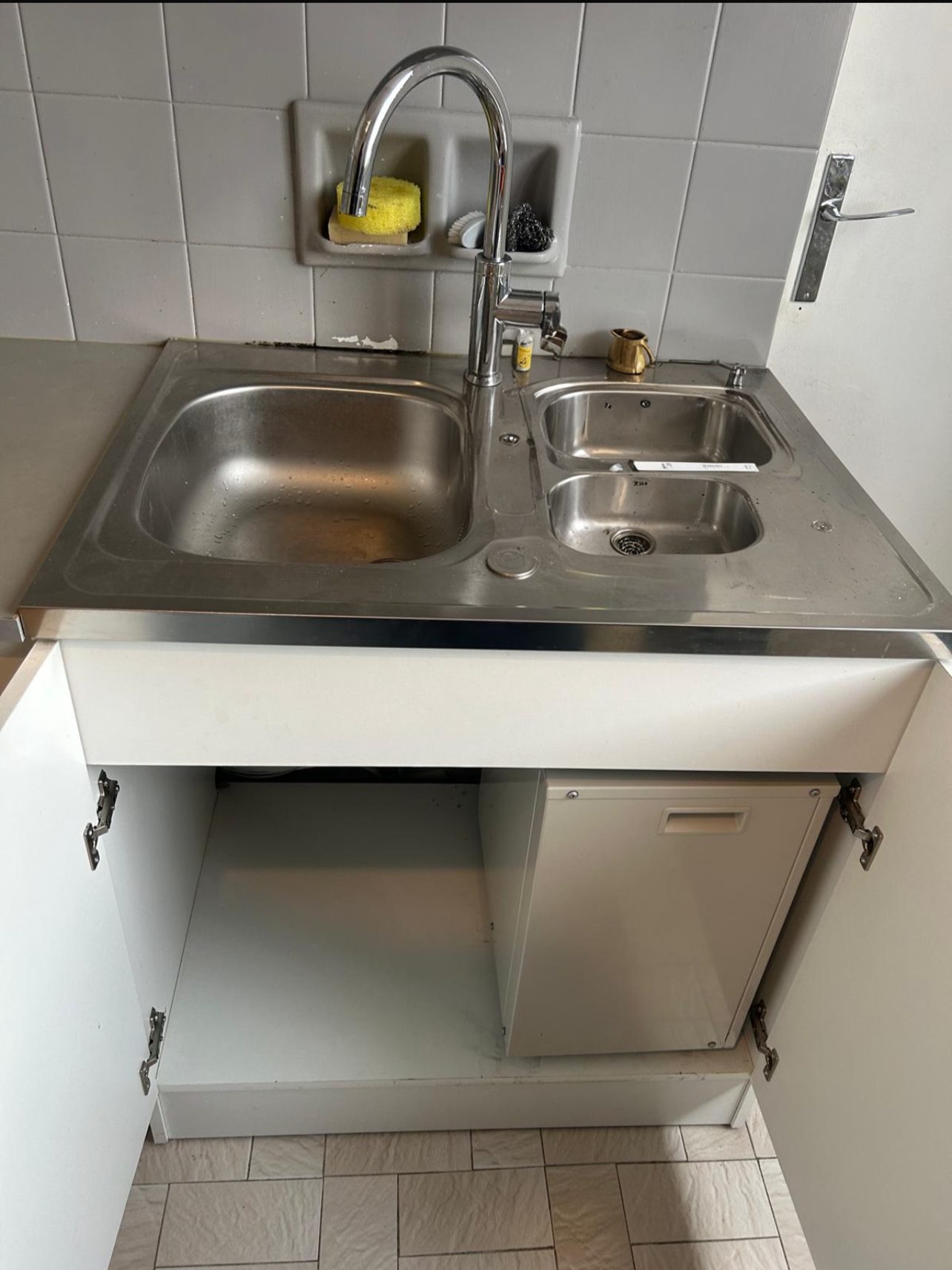 Meuble sous évier ouvert abritant une unité de climatisation compacte