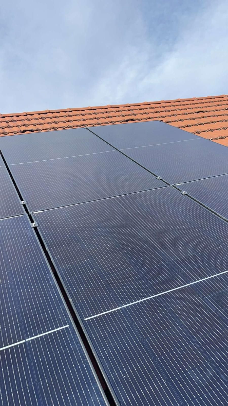 Gros plan sur des modules photovoltaïques posés sur un toit en tuiles