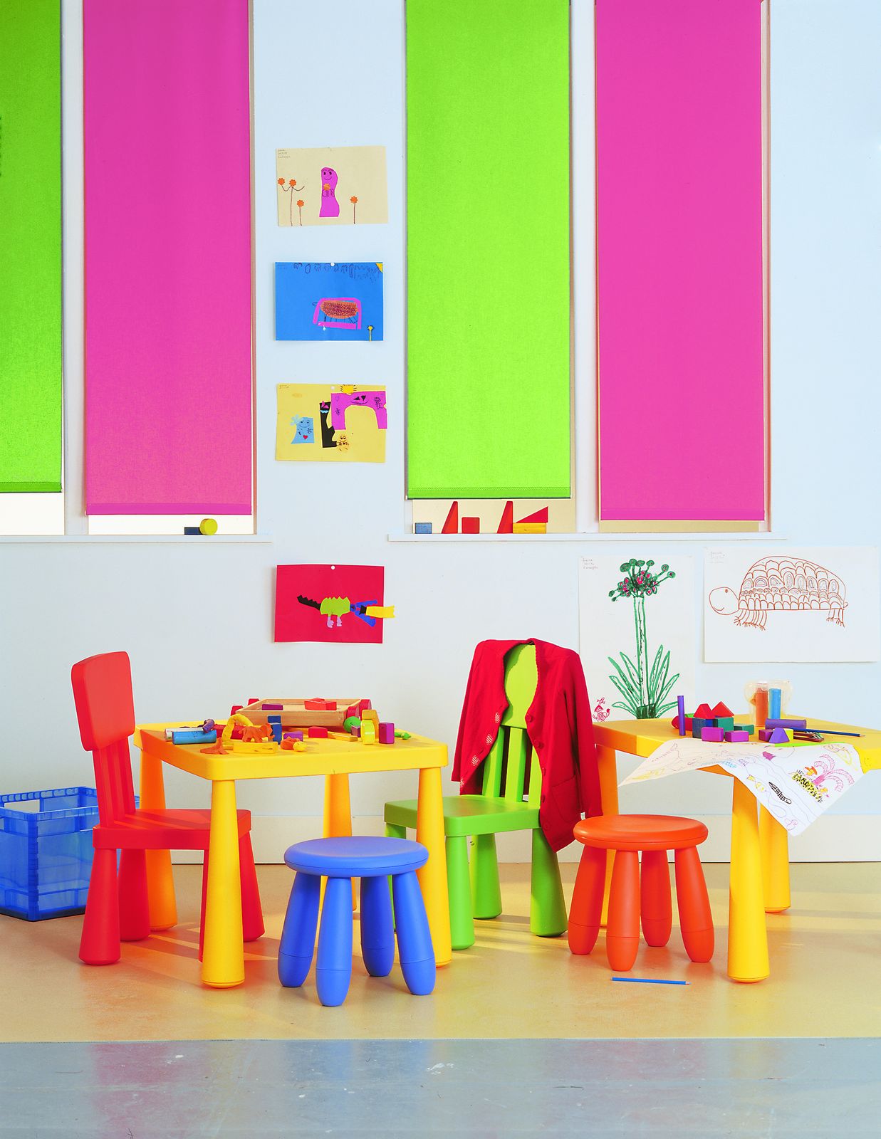 Stores enrouleurs rose et vert anis baissés dans une chambre d'enfant aux meubles colorés