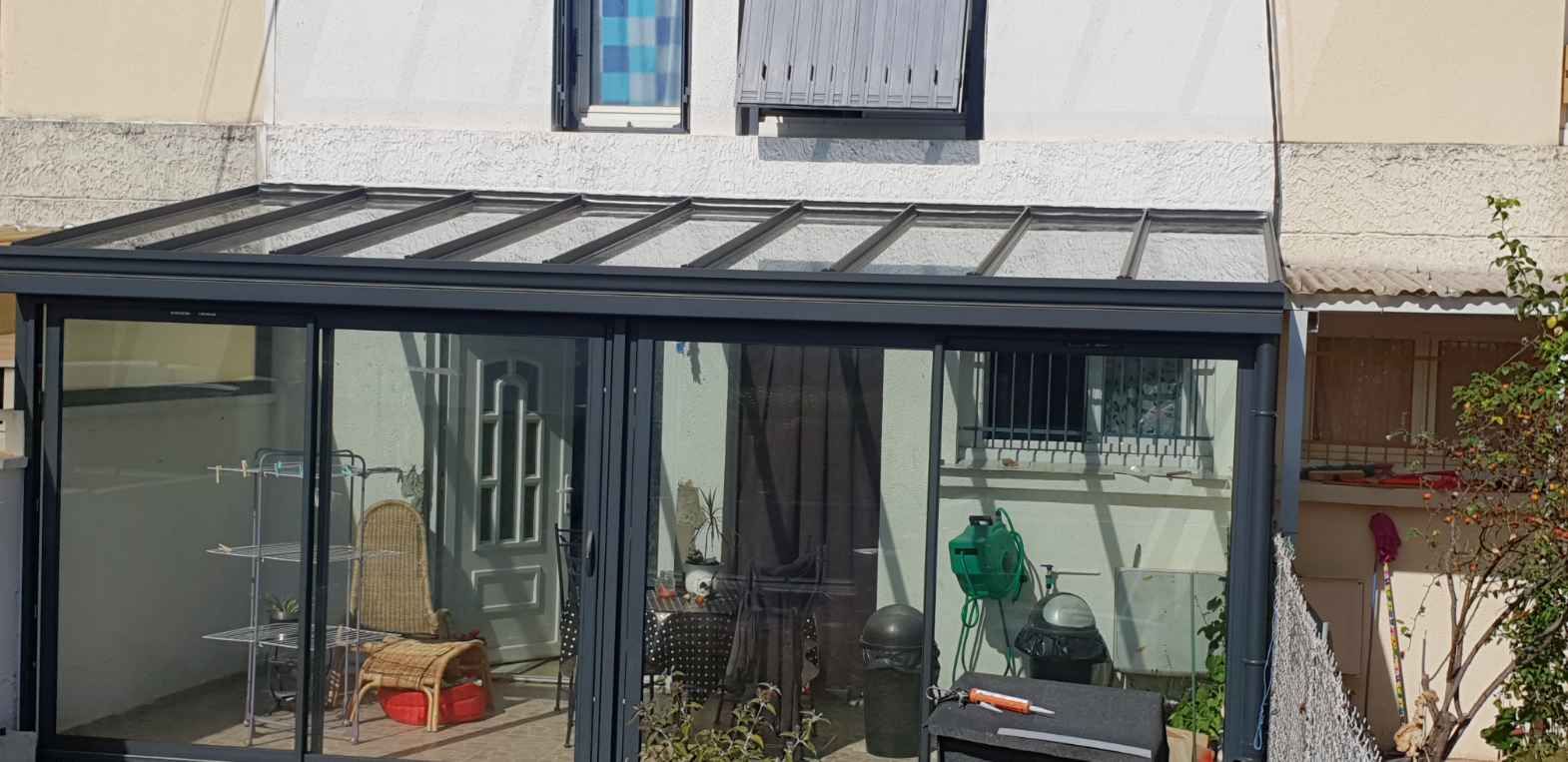 Véranda aluminium gris anthracite à toiture vitrée accolée à une maison de ville