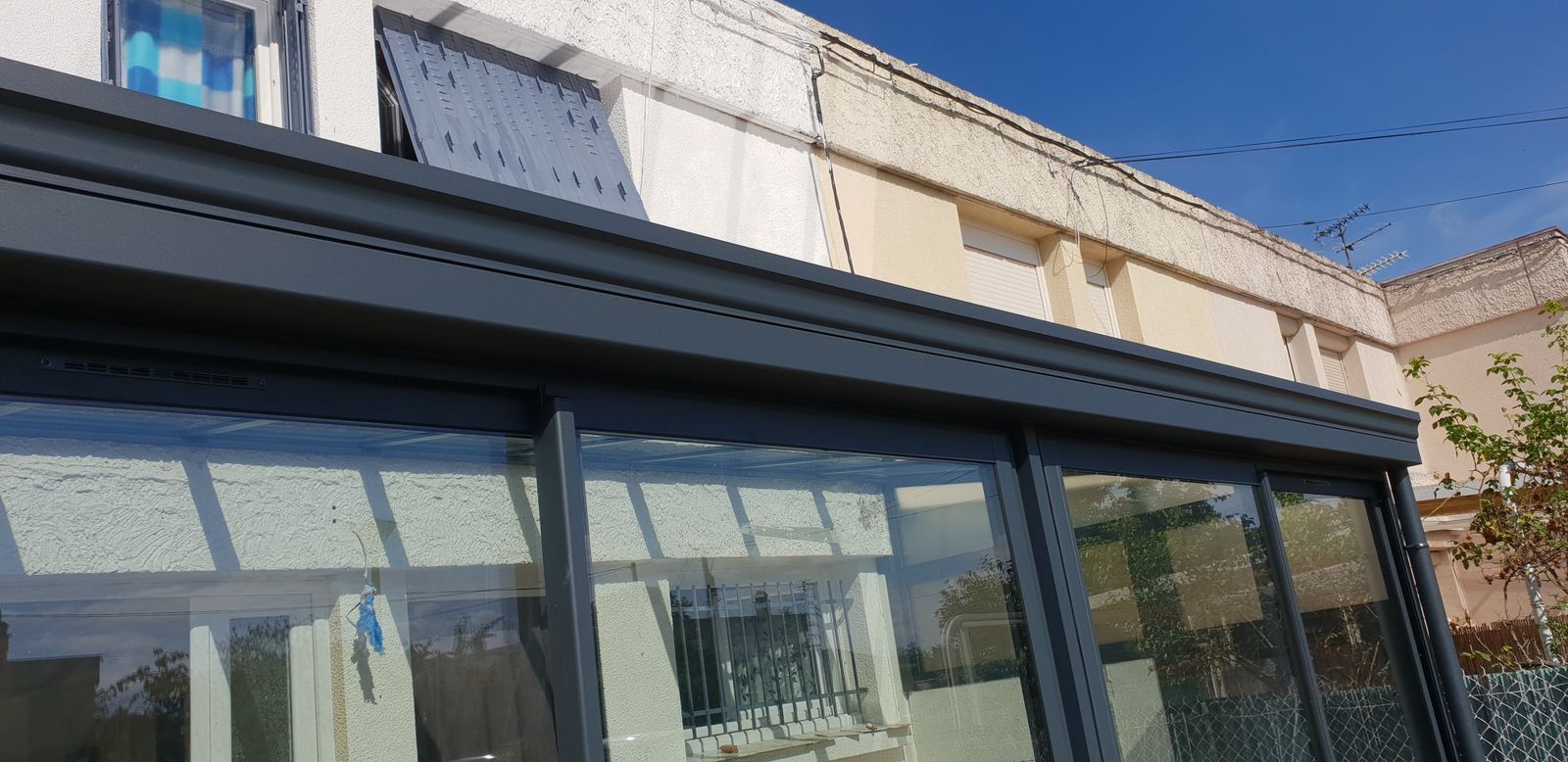 Véranda en aluminium gris anthracite vue de l'extérieur, grands panneaux vitrés